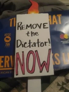 Protest sign says: Remove the Dictator NOW!